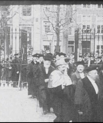 Albert Einstein draagt zijn toga van de universiteit van Berlijn met daarover de kappa van de universiteit van Madrid. Naast hem loopt Ehrenfest