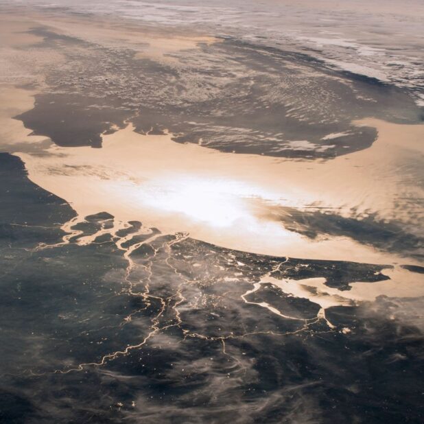 Nederland gezien vanuit het ruimtestation ISS. In de reflectie van het zonlicht tekent de rivierendelta zich scherp af tegen het donkere land