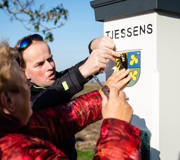 Wethouder Pytsje de Graaf bevestigt het bordje op een van de hekpalen van State Tjessens